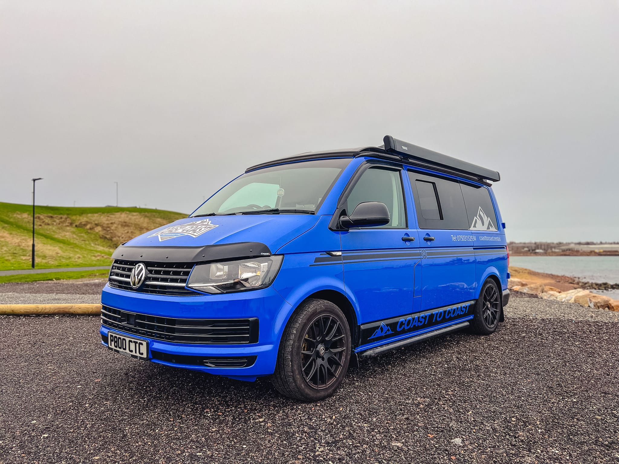 Blue VW T6 Coast to Coast campervan with branding, parked by the coast near Peterhead, Scotland – available for campervan hire