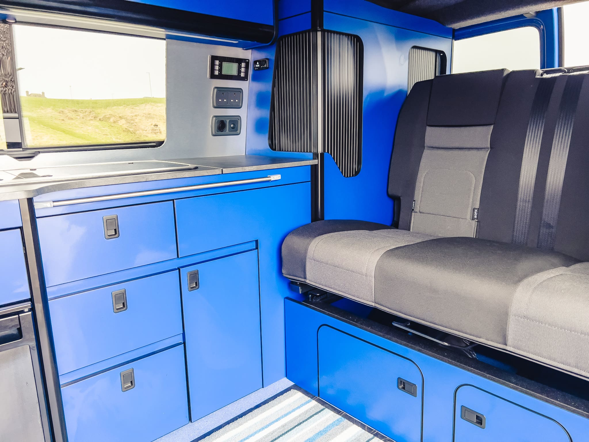 VW T6 campervan interior with fold-out seating, kitchen units, and storage – Coast to Coast motorhome rental Peterhead, Scotland