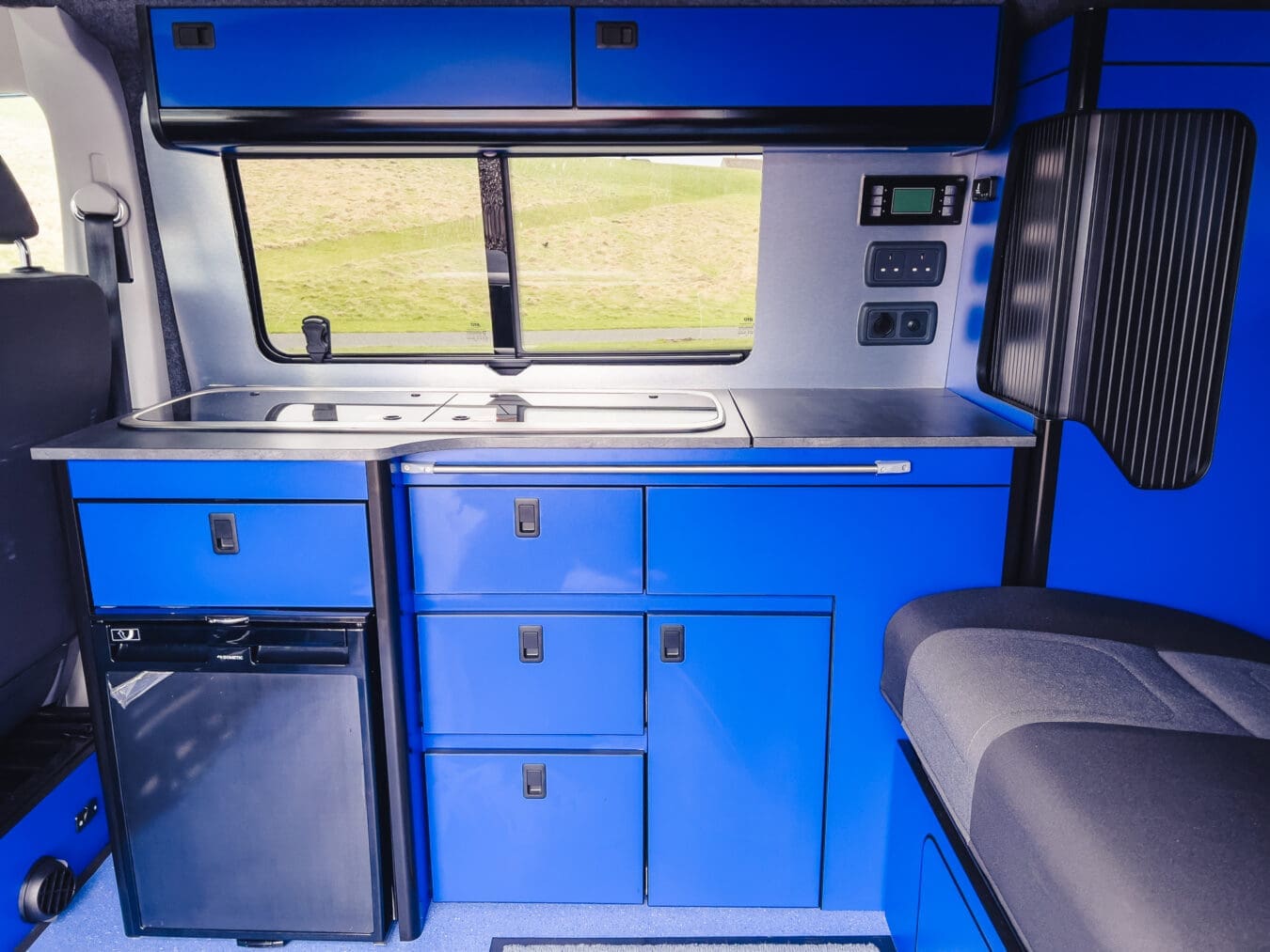 Home 25 Modern motorhome rental interior with blue kitchen units, fridge, and sink – Coast to Coast Peterhead, Scotland