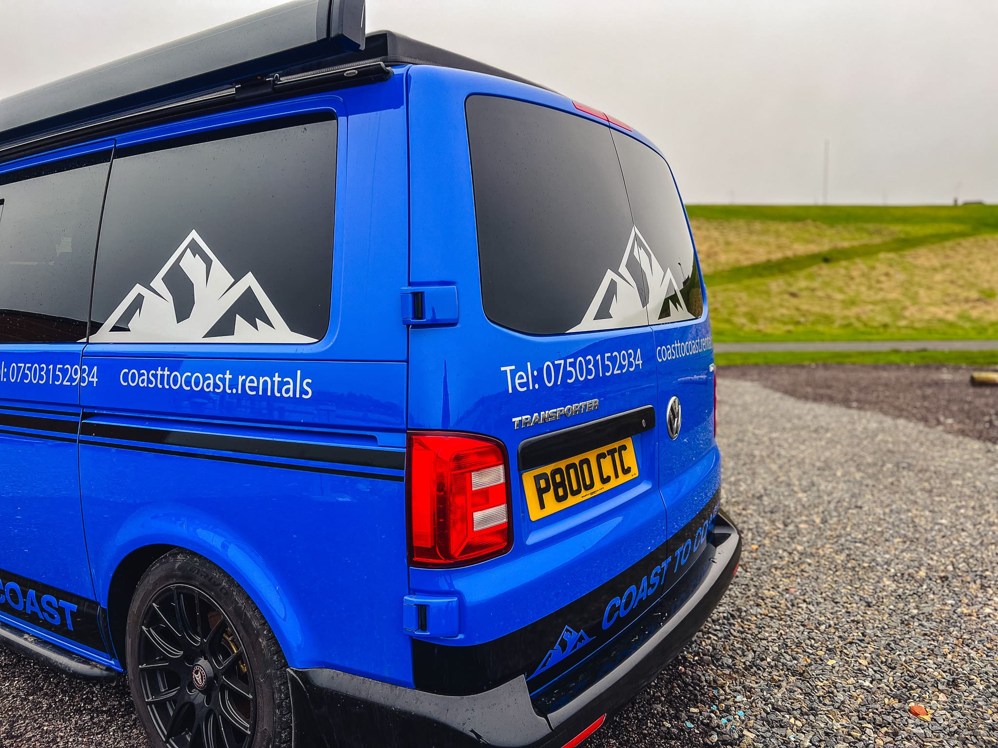 rear view of blue Coast to Coast VW campervan with company branding, phone number, and website – available for motorhome hire in Peterhead, Scotland
