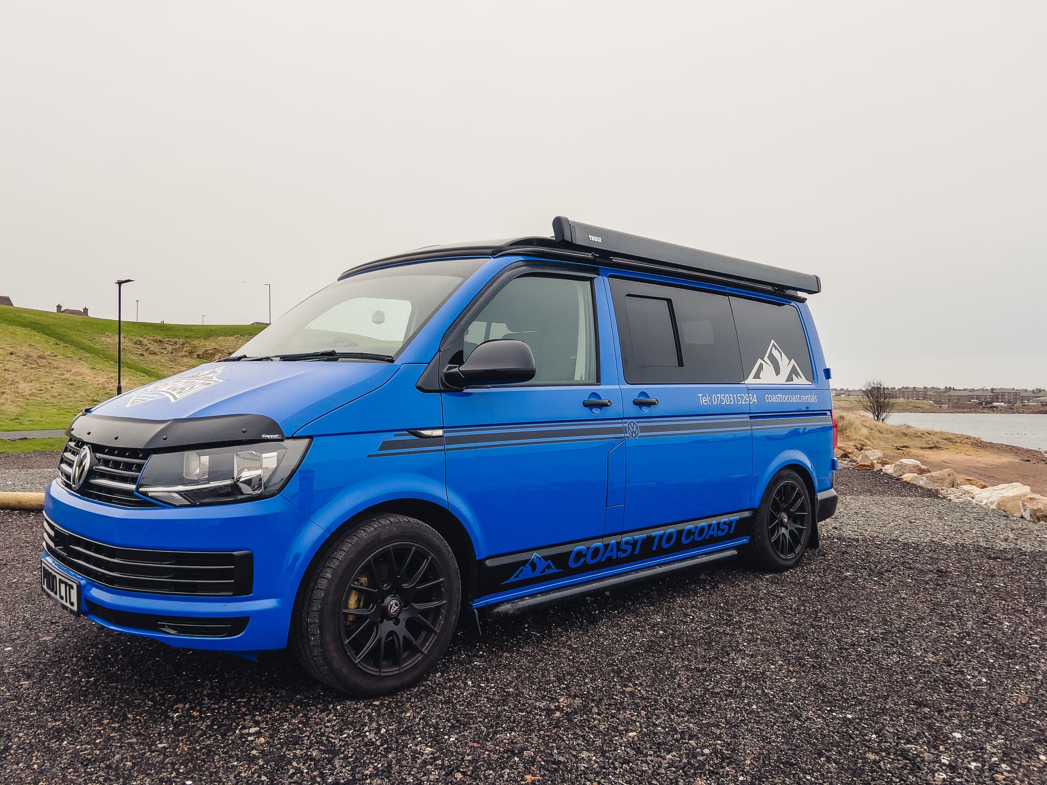 Blue VW T6 Coast to Coast campervan with branding, parked by the coast near Peterhead, Scotland – available for campervan hire